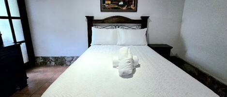 A neatly made bed with a white bedspread and a decorative pillow.