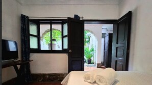 Une chambre d’hôtel avec un lit, une télévision, une fenêtre et une porte donnant sur une cour intérieure.