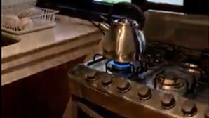 Une cuisine équipée d’une cuisinière à gaz, d’une bouilloire et d’une fenêtre avec des vitres dépolies.