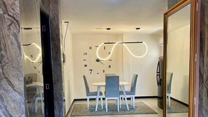 En modern inredning med en matplats som har ett vitt bord och stolar, en stor spegel och en unik lampa i taket.