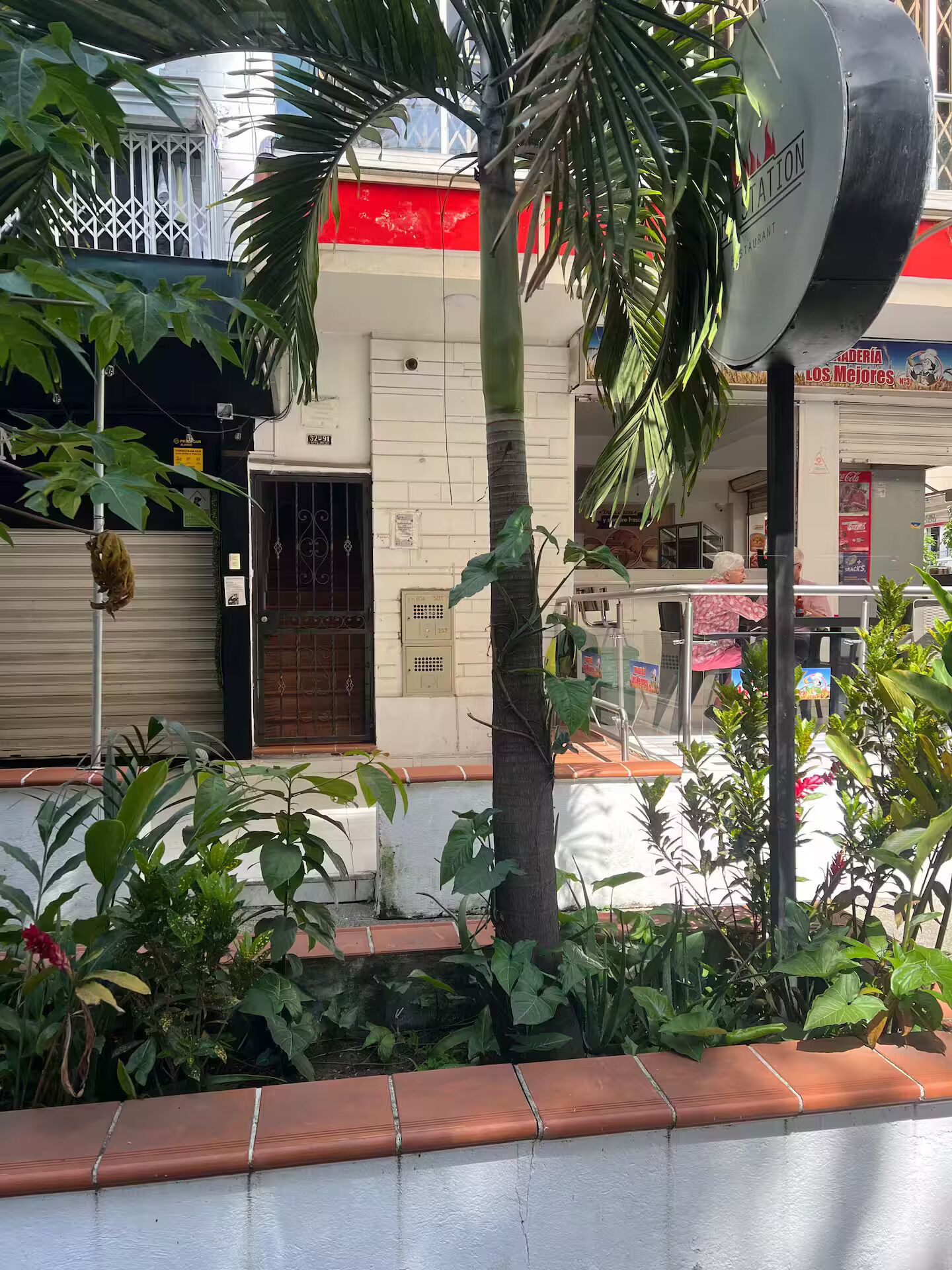 Un edifici amb una tenda vermella, una porta metàl·lica i un rètol que diu "COSTA".