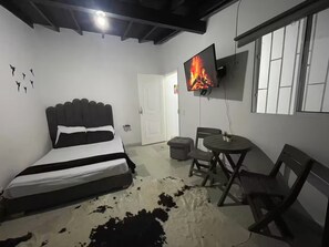 Ein Schlafzimmer mit einem Bett, einem an der Wand montierten Fernseher, einem kleinen Tisch mit Stühlen und einem Kuhfellteppich.