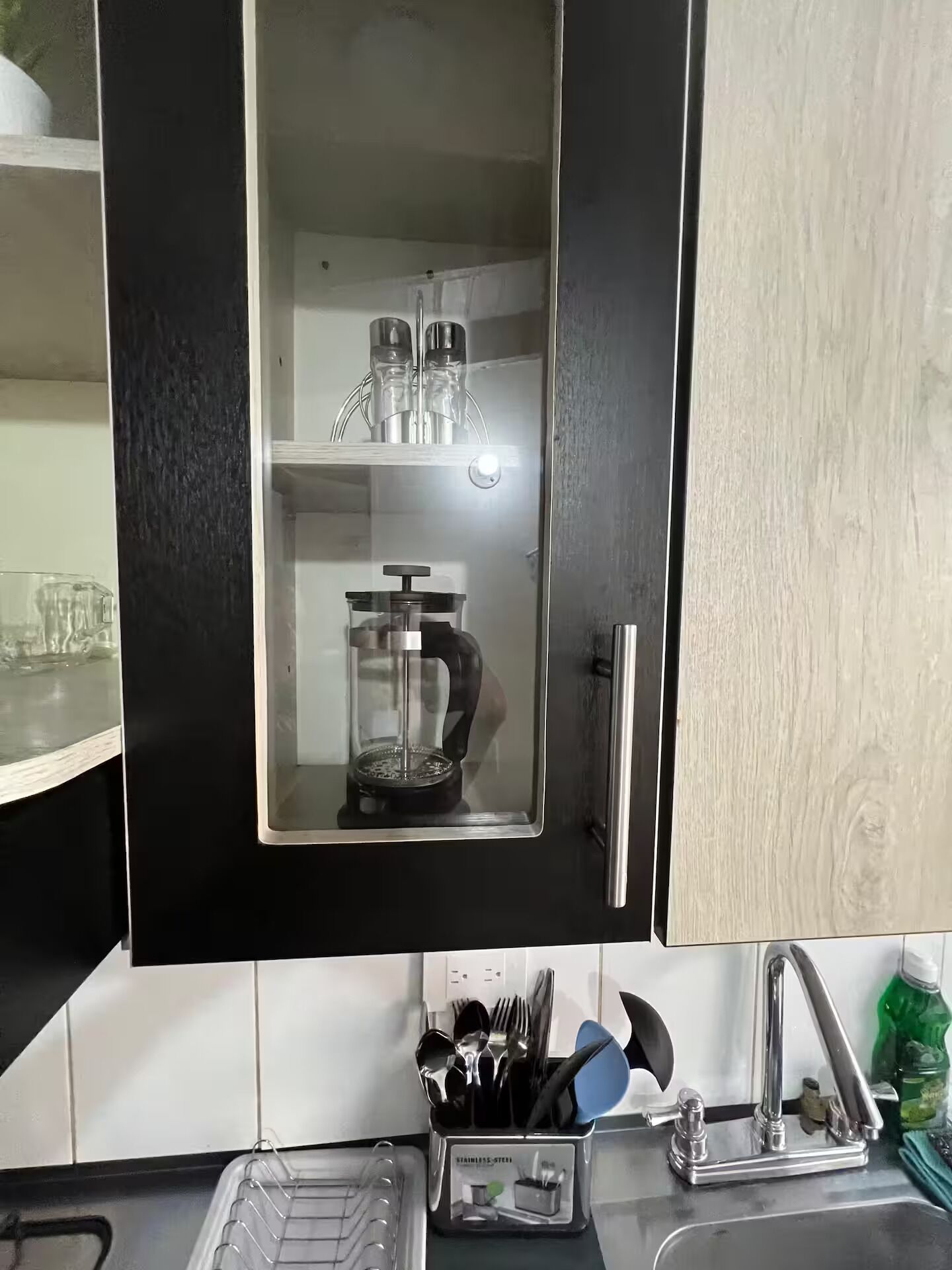Eine Küche mit einem schwarzen Schrank, der ein Gewürzregal und eine Kaffeemaschine beherbergt.