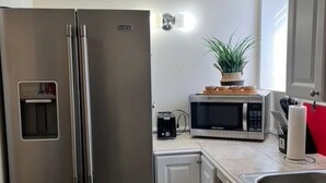 A compact kitchen with a stainless steel refrigerator, a microwave, and a coffee maker on the countertop. - Alaska Tucked Inn-The Den ; Cozy 1 bedroom with all the touches of home! (Fairbanks)