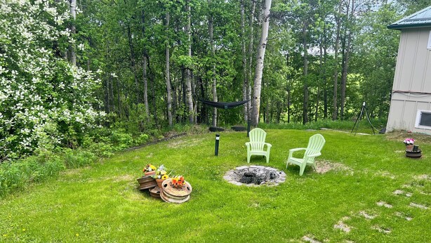A backyard with a fire pit, two green chairs, and a small shed. - Alaska Tucked Inn-The Den ; Cozy 1 bedroom with all the touches of home! (Fairbanks)