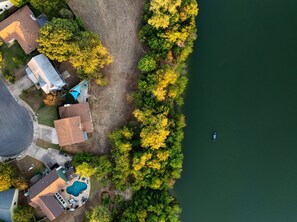 An aerial view of a residential area with a swimming pool, a boat on the water, and a forested area. - Lake Access and Pool in the heart of Domain (Austin)