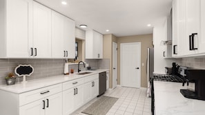 A modern kitchen with white cabinets, a stainless steel refrigerator, and a black stove. - Lake Access and Pool in the heart of Domain (Austin)