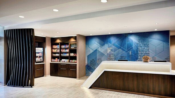 A modern reception area with a counter, bookshelves, and a decorative wall. - SpringHill Suites by Marriott Bryce Canyon (Bryce Canyon)