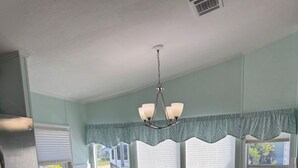 Uma cozinha com ilha central, mesa de jantar com cadeiras e lustre.