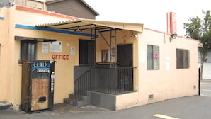A building with an office sign, a vending machine, and a storefront. - Parklane Motel (Oakland)