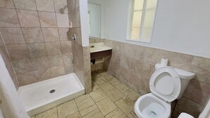 A bathroom with a shower, toilet, sink, and a window. - Parklane Motel (Oakland)