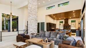 A spacious living room with a large sofa, wooden coffee table, and a stone pillar. - Swanky Chalet with Sauna, HotTub, EpicView, Golf, King Suite (Blue Ridge)