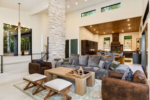 A spacious living room with a large sofa, wooden coffee table, and a stone pillar. - Swanky Chalet with Sauna, HotTub, EpicView, Golf, King Suite (Blue Ridge)