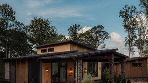 A modern two-story house with a stone foundation, a large front porch, and a well-maintained garden. - Swanky Chalet with Sauna, HotTub, EpicView, Golf, King Suite (Blue Ridge)