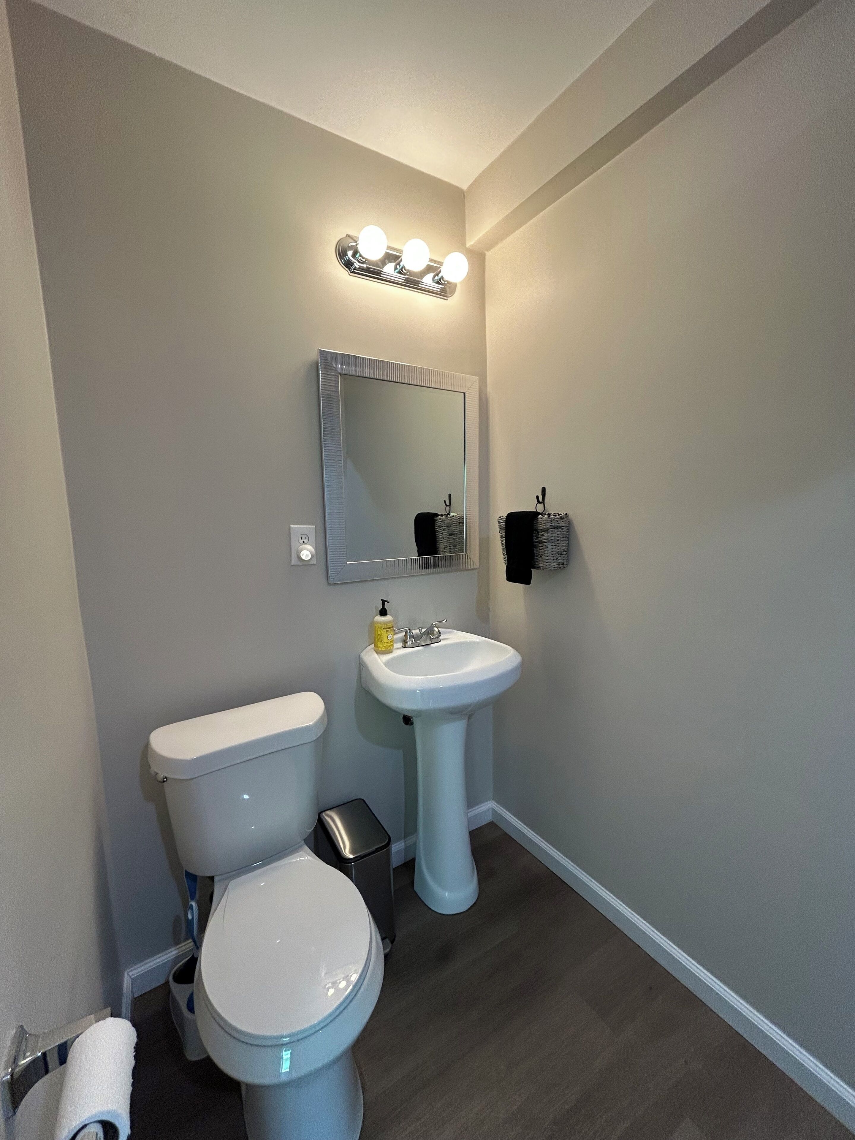 A bathroom with a toilet, sink, and vanity mirror.