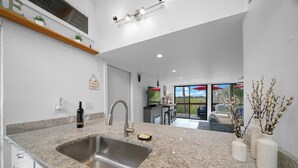 A modern kitchen with granite countertops, a stainless steel sink, and a wine bottle. - B1 - Riverview Bungalow (Crystal River)