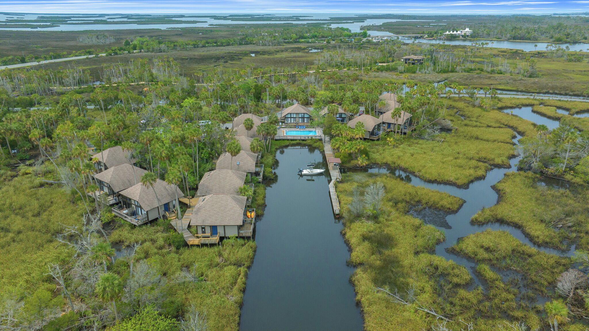 A riverside property with multiple houses connected by a waterway, surrounded by marshland.