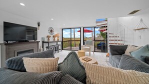 A modern living room with a flat-screen TV, a fireplace, and a large window overlooking a scenic landscape. - B1 - Riverview Bungalow (Crystal River)