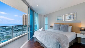 Ein modernes Hotelzimmer mit einem großen Bett, einem Nachttisch mit Lampe und Blick auf die Stadt durch raumhohe Fenster.