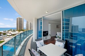 Un balcon avec une piscine, un coin repas et un téléviseur.