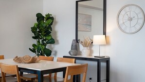 Ein Essbereich mit Tisch, Stühlen, einer Topfpflanze, einer Lampe und einer Wanduhr.