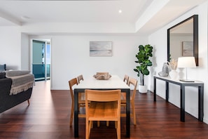 Un espace repas moderne avec une table blanche, des chaises en bois et une plante en pot.