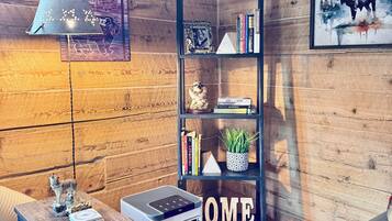 Ein gemütliches Zimmer mit Holzwänden, einem Bücherregal, einem Schreibtisch mit Computer und einem blauen Ledersofa.