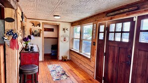 Een houten interieur met een plafond vol ingewikkelde versieringen, een rode bar met krukken en een grote houten deur.