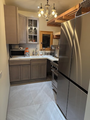 A kitchen with a stainless steel refrigerator, a microwave, and a stove. There is a wooden ceiling and a chandelier. - Amazing 4-bedroom home with AC in downtown San Rafael (San Rafael)