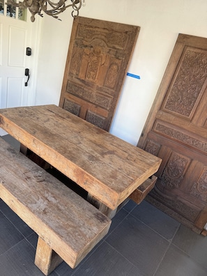 A rustic wooden table with a bench, positioned in front of a door with intricate carvings. - Amazing 4-bedroom home with AC in downtown San Rafael (San Rafael)