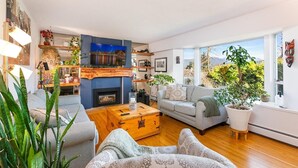 Una sala de estar moderna con chimenea, un sofá, una mesa de centro y un ventanal con vistas al exterior.
