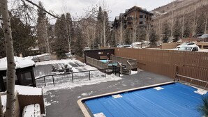 A swimming pool with a blue cover, surrounded by a wooden deck and a fence. - Walk to Vail Village 1BR Condo w/ Free Shuttle to the Slopes (Vail)