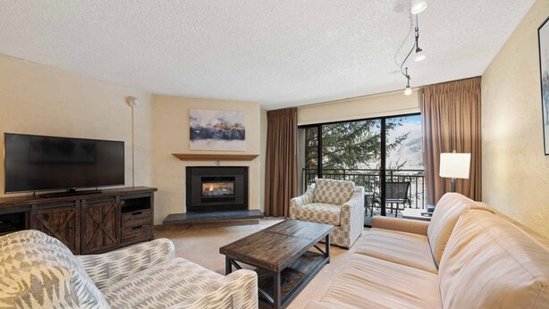 A living room with a fireplace, a television, and a sofa. - Walk to Vail Village 1BR Condo w/ Free Shuttle to the Slopes (Vail)