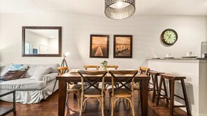 Un coin repas avec une table et des chaises en bois, un miroir et une horloge au mur.