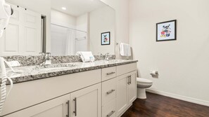 Une salle de bain avec un comptoir en marbre, un lavabo, des toilettes et un espace douche.