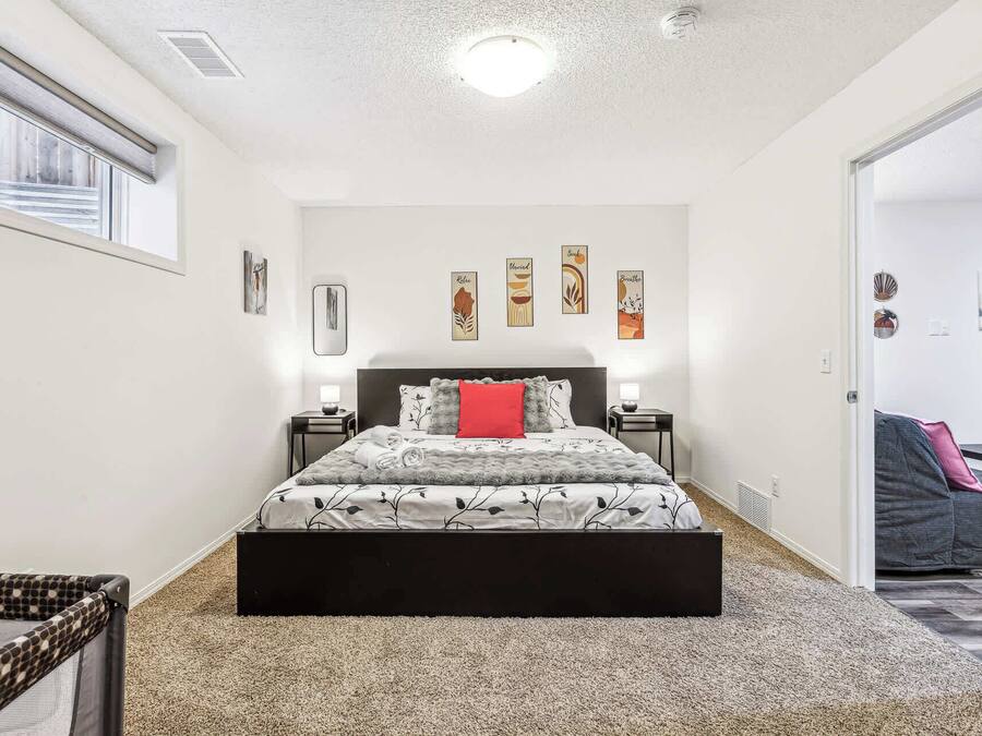 Een slaapkamer met een bed, twee nachtkastjes, een raam en wanddecoratie.