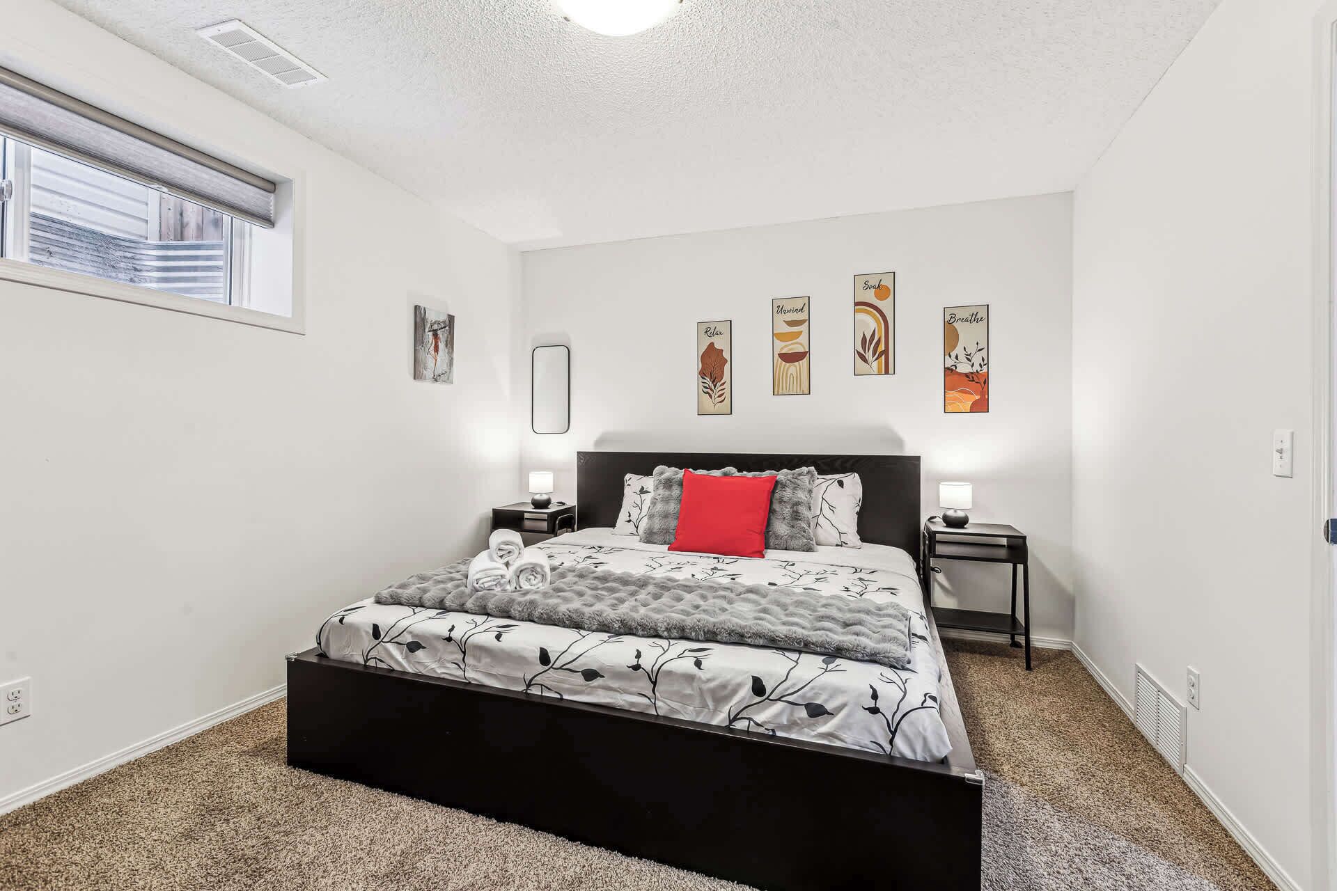 A bedroom with a bed, bedside tables, and wall art.