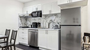 A modern kitchen with white cabinets, a stainless steel refrigerator, a microwave, and a dishwasher. - Charming Basement Suite With Parking & Laundry (Calgary)
