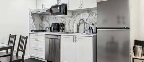 A modern kitchen with white cabinets, a stainless steel refrigerator, a microwave, and a dishwasher.