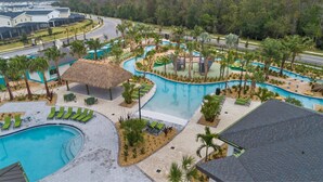 Ein Resort mit einem großen Schwimmbad, mehreren Liegebereichen und einem strohgedeckten Gebäude.