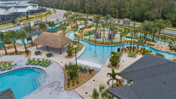 Un resort con una grande piscina, diverse zone relax e una struttura con tetto di paglia.