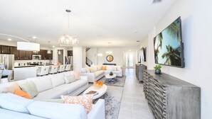 Ein modernes Wohnzimmer mit einer großen Eckcouch, einem Couchtisch und einem Essbereich, mit einer Küche im Hintergrund.