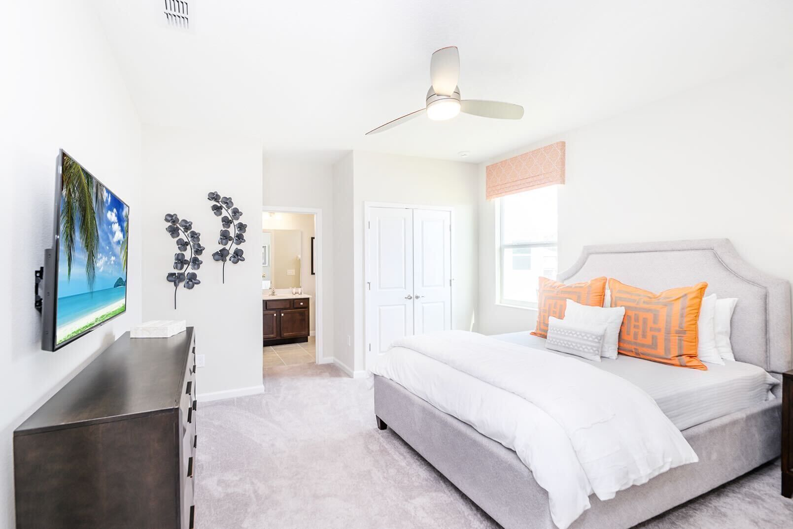 Une chambre à coucher moderne avec un lit, un ventilateur de plafond et un téléviseur fixé au mur.