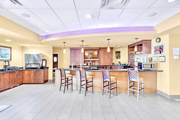 A bar area with a counter, stools, and a television.