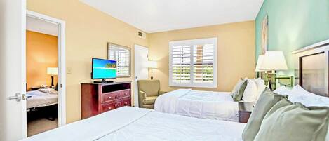 A hotel room with two beds, a television, a desk, and a chair.