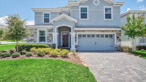 A two-story house with a stone facade, a front porch, and a garage. - 8BR Luxury Sleeps 22 w Pool & Hot Tubnear Disney (Davenport)