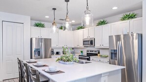 A modern kitchen with white cabinets, stainless steel appliances, and pendant lighting. - Upstay: Luxury 10br Mansion w Pool,hot Tub & Games (Kissimmee)
