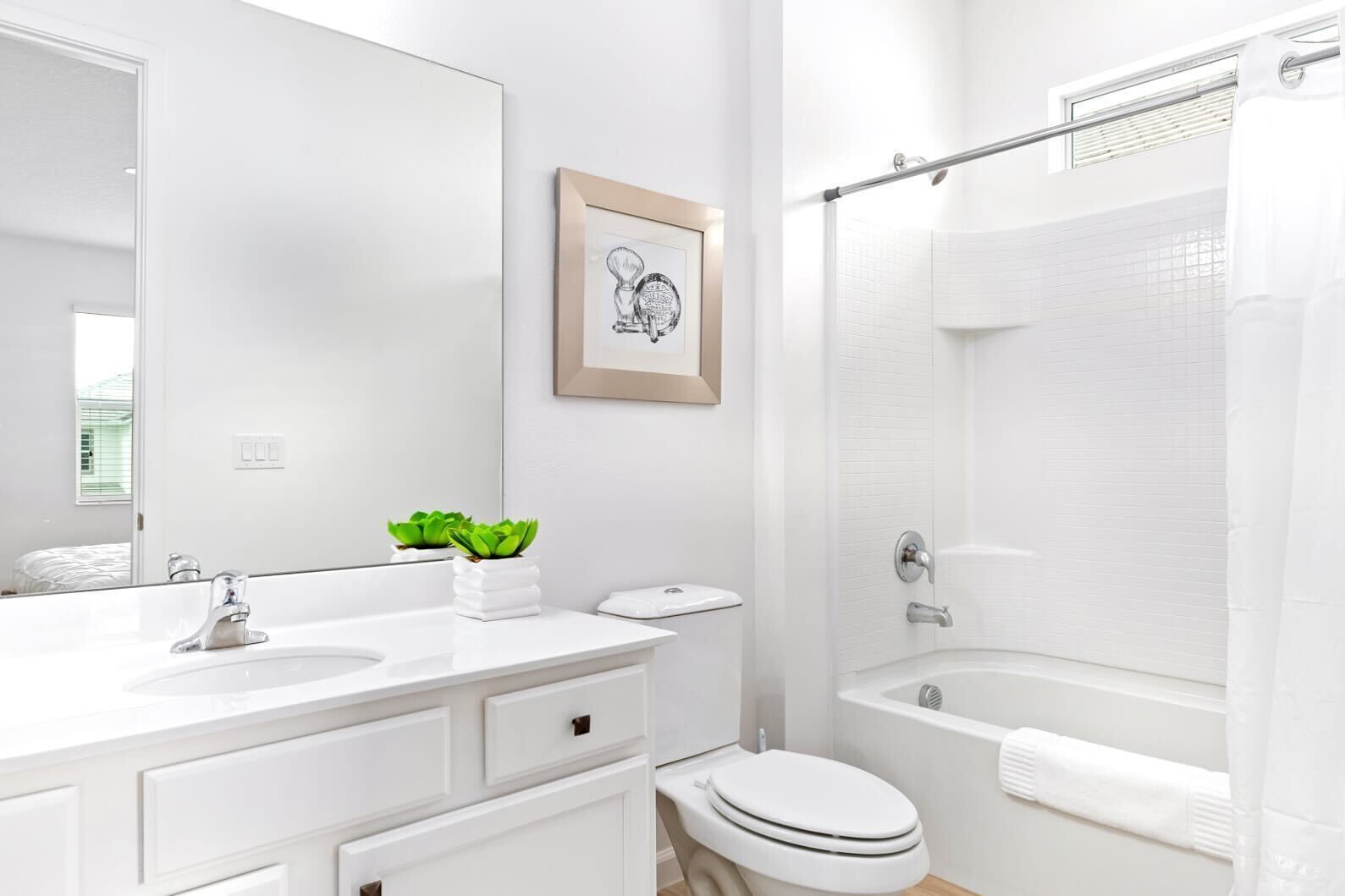A modern bathroom with a white vanity, a toilet, a bathtub, and a shower.