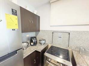 Eine kompakte Küche mit Kühlschrank, Herd, Kaffeemaschine und Toaster.
