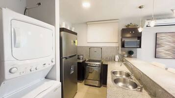 Cocina compacta con refrigerador, horno, microondas y pileta.